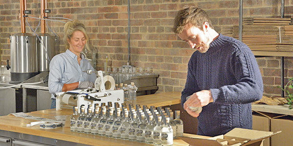 Picture of Jess and Luke putting labels on the completed Whitby Gin bottles