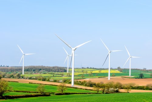 Wind turbines with a background of green fields to represent sustainable business.