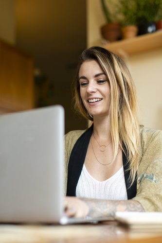 A blonde woman looking at her laptop to learn more about returning from maternity leave.