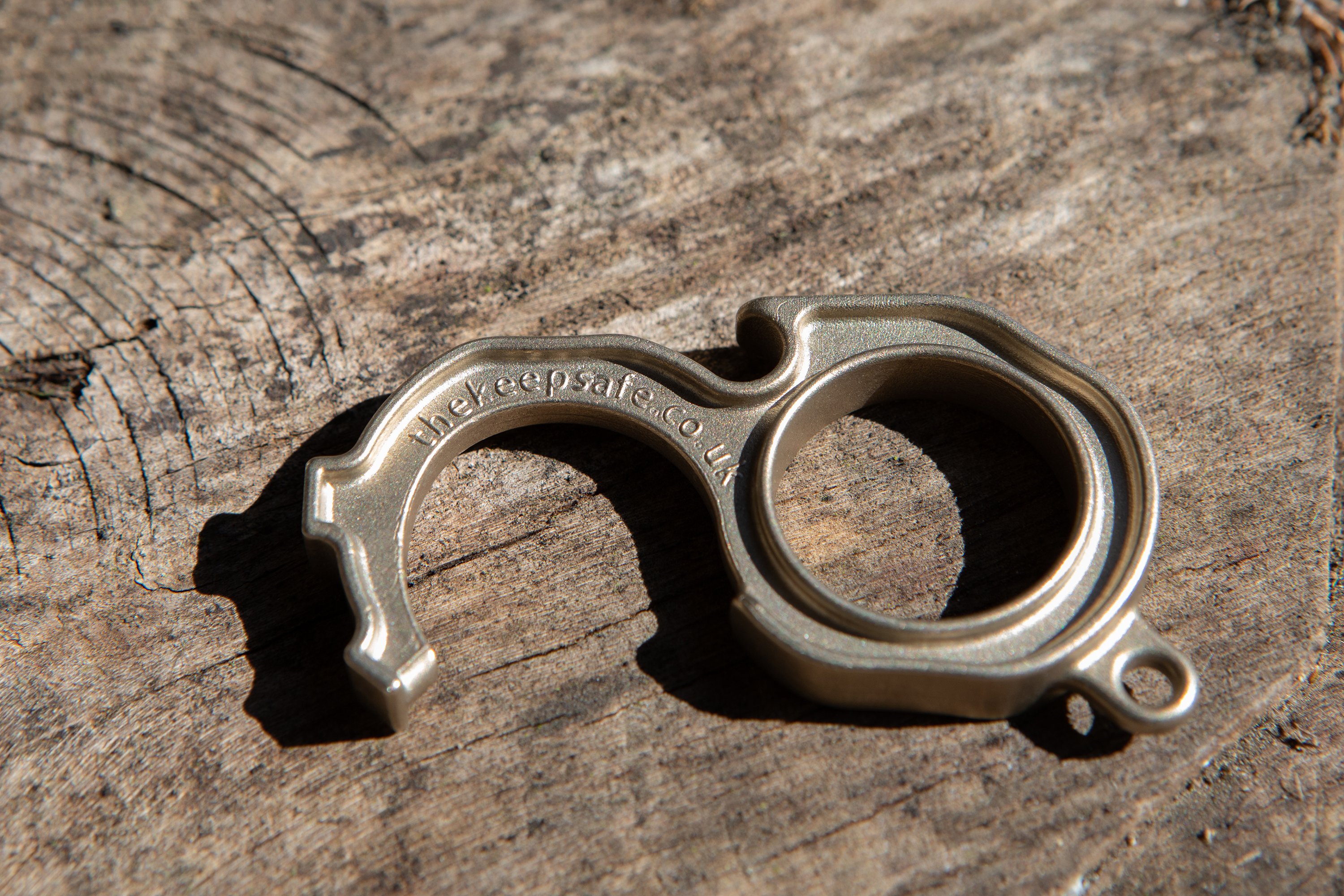 Image of the Keepsafe, which looks like a chunky ring, with a sort of semi-circular hook extending out, to allow people to engage with items without touching them. It is a light copper colour.