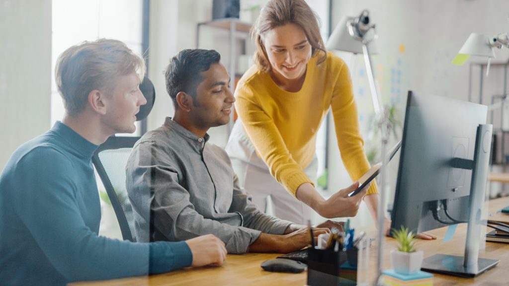 A female business support manager in Harrogate is showing a tablet computer to two men.