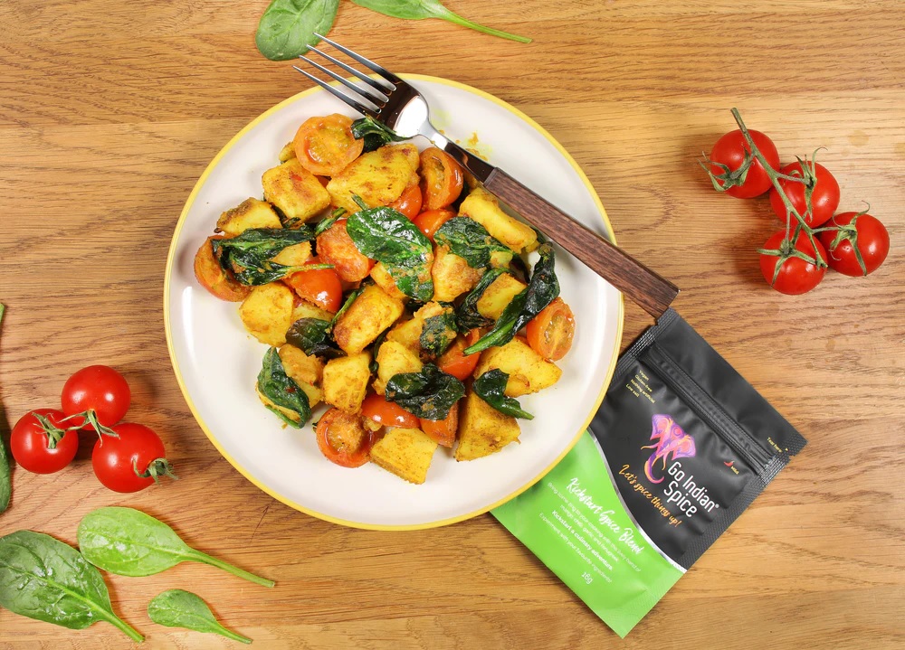 A picture of potatoes and vegetables next to a packet of Go Indian Spice mix