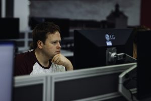 A man looks thoughtfully at a computer monitor in an office environment